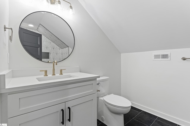 bathroom featuring toilet, vanity, vaulted ceiling, and tile patterned floors