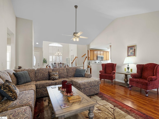 living room with vaulted ceiling, a healthy amount of sunlight, ceiling fan with notable chandelier, and hardwood / wood-style floors