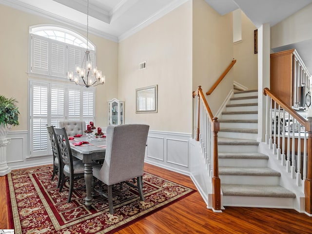 dining space with wood-type flooring, crown molding, and a chandelier