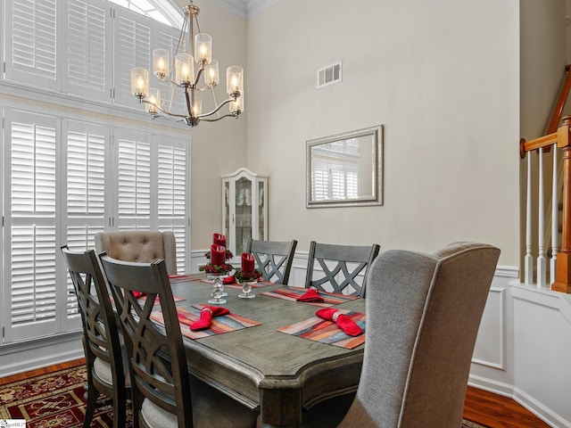 dining area featuring dark hardwood / wood-style flooring, ornamental molding, and a notable chandelier