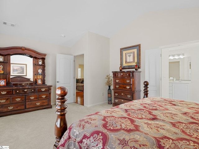 bedroom featuring light carpet, vaulted ceiling, and ensuite bath