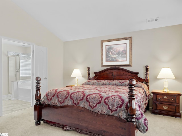 bedroom with ensuite bathroom, light carpet, and vaulted ceiling