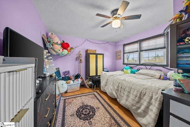 bedroom with ceiling fan, hardwood / wood-style floors, and a textured ceiling