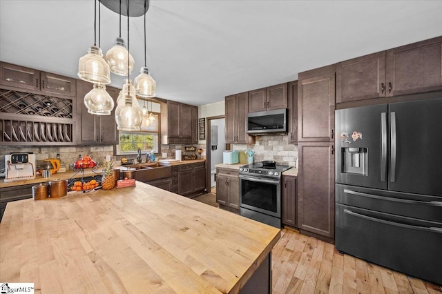 kitchen with wood counters, stainless steel appliances, decorative backsplash, dark brown cabinetry, and sink