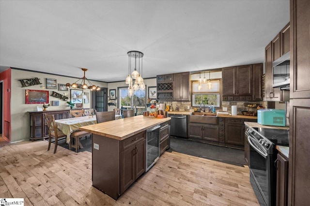 kitchen with appliances with stainless steel finishes, dark brown cabinets, wine cooler, hanging light fixtures, and sink