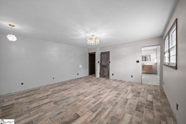 unfurnished room featuring a chandelier and light hardwood / wood-style floors