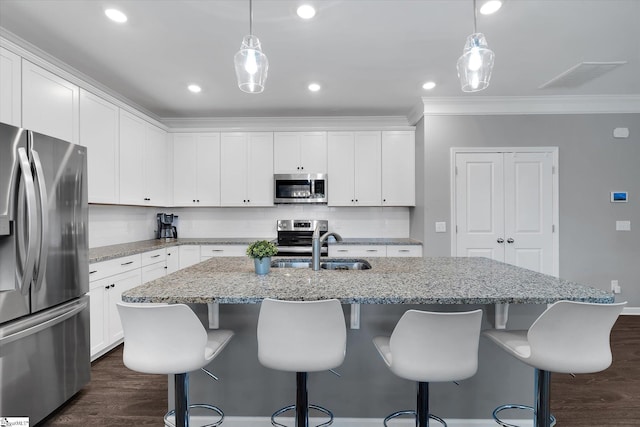 kitchen with hanging light fixtures, sink, white cabinets, an island with sink, and stainless steel appliances