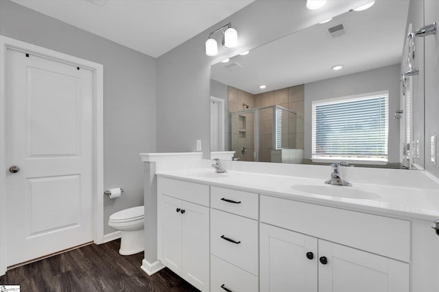 bathroom featuring hardwood / wood-style floors, a shower with door, toilet, and vanity