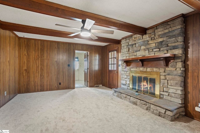 unfurnished living room featuring beamed ceiling, wood walls, and carpet