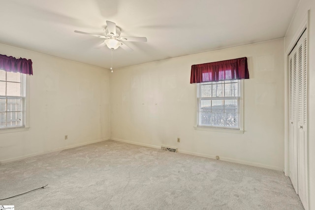 unfurnished bedroom with ceiling fan, multiple windows, and light carpet