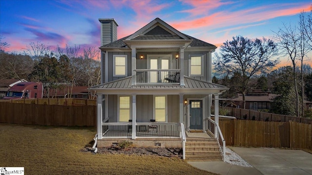 view of front of property featuring a balcony, a porch, and a yard