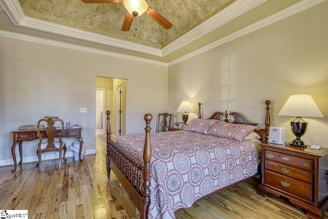 bedroom with ceiling fan, light hardwood / wood-style floors, a raised ceiling, and crown molding