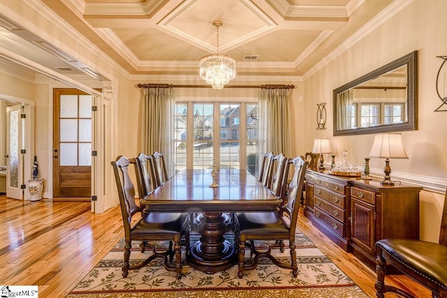 dining space with light wood-type flooring, coffered ceiling, a chandelier, and crown molding