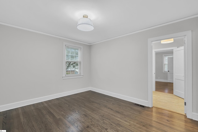 spare room with a healthy amount of sunlight, dark hardwood / wood-style floors, and ornamental molding