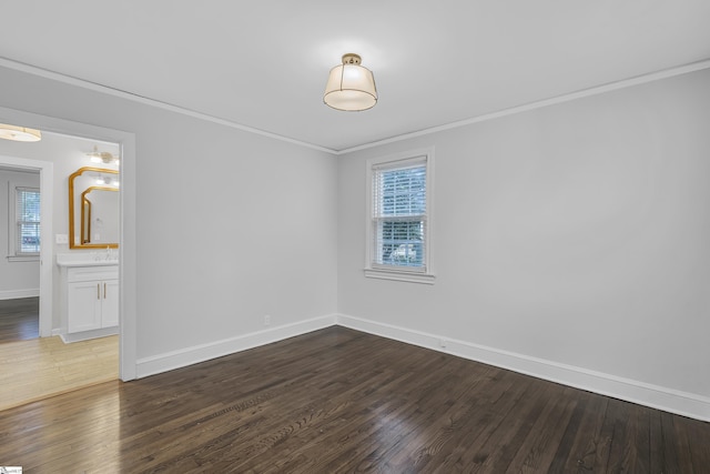 spare room with dark wood-type flooring, sink, and ornamental molding