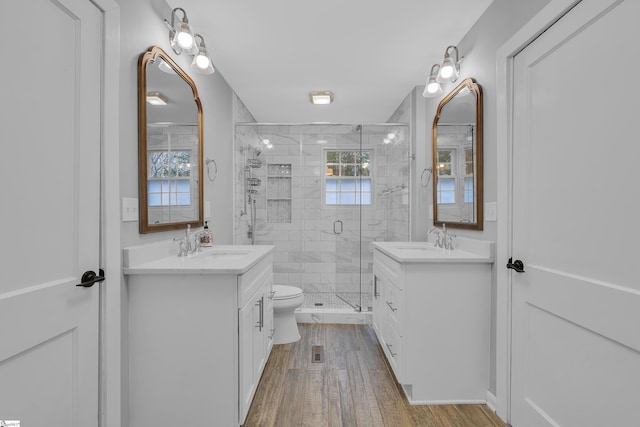 bathroom featuring vanity, toilet, hardwood / wood-style floors, and a shower with door