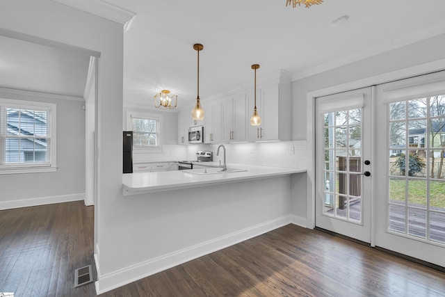 kitchen featuring white cabinets, stainless steel appliances, french doors, hanging light fixtures, and kitchen peninsula