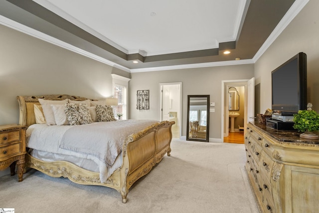 bedroom with light colored carpet, crown molding, a raised ceiling, and connected bathroom