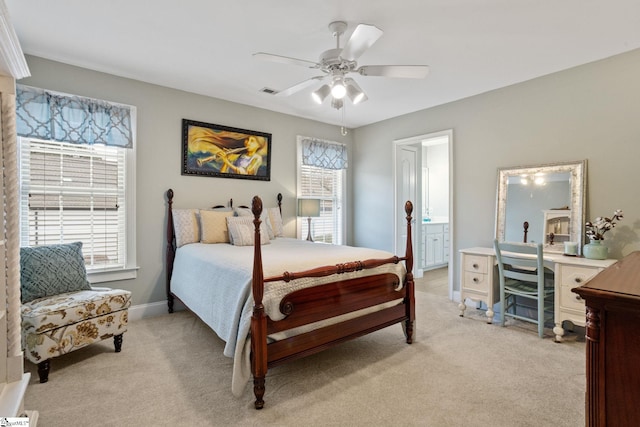 bedroom featuring ceiling fan, light colored carpet, and ensuite bath