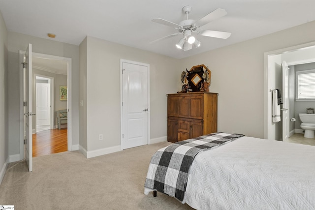 bedroom featuring ceiling fan, light colored carpet, and ensuite bath