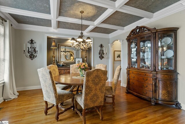 dining area featuring hardwood / wood-style floors, ornamental molding, decorative columns, beam ceiling, and coffered ceiling