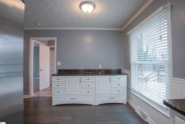 kitchen featuring white cabinets, crown molding, and dark stone countertops