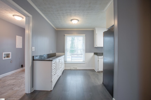 kitchen featuring fridge, a textured ceiling, white cabinetry, ornamental molding, and dark wood-type flooring