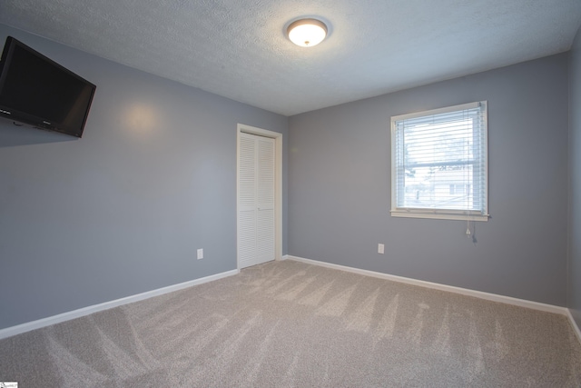 carpeted empty room featuring a textured ceiling