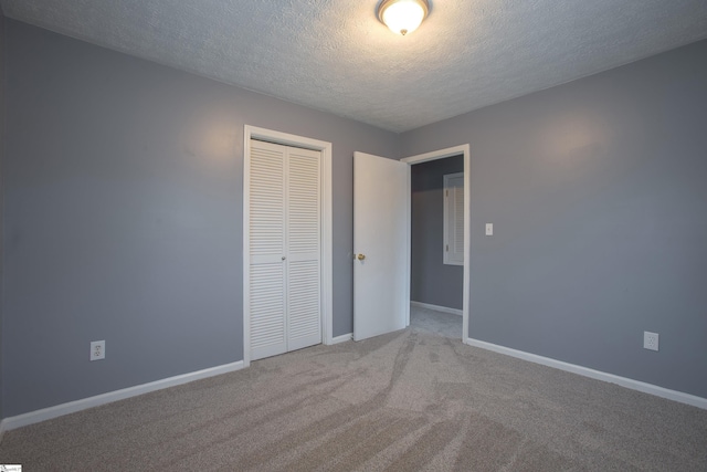 unfurnished bedroom featuring a textured ceiling, a closet, and light carpet