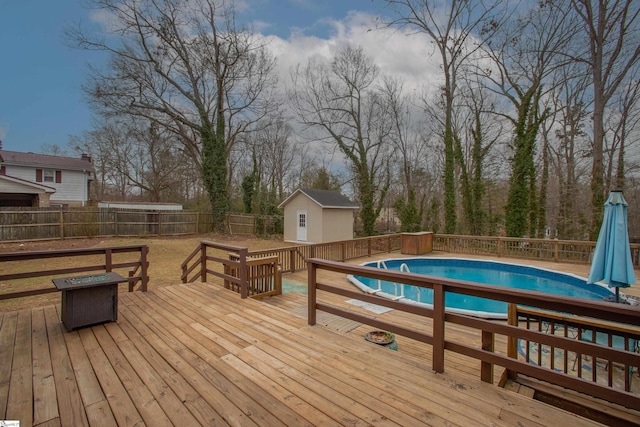 view of swimming pool with a fire pit, a wooden deck, and a storage shed