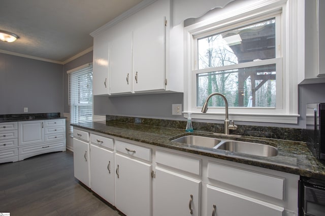 kitchen with white cabinetry, dark hardwood / wood-style flooring, dark stone countertops, sink, and ornamental molding