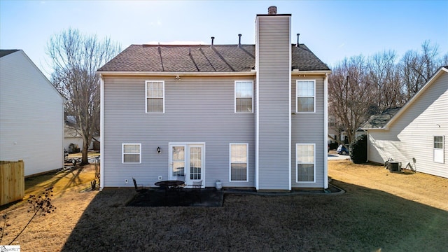 rear view of house with central AC unit and a yard