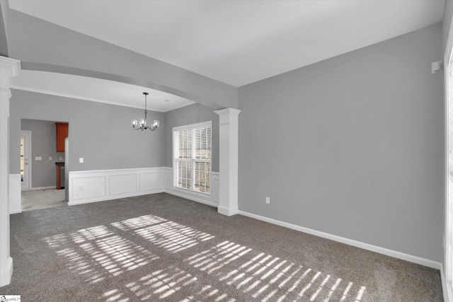 carpeted spare room with a chandelier and ornate columns