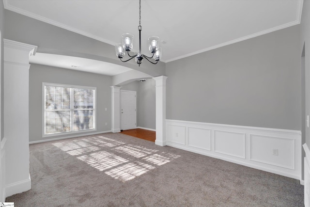 unfurnished dining area with decorative columns, carpet flooring, ornamental molding, and a notable chandelier