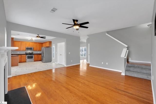 unfurnished living room with sink, ceiling fan, and light hardwood / wood-style floors