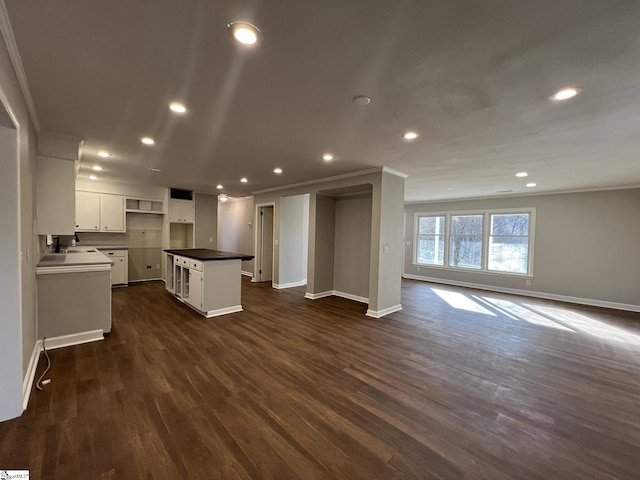 kitchen featuring crown molding, white cabinetry, sink, a kitchen island, and dark hardwood / wood-style flooring