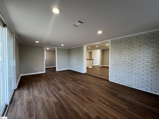 empty room with brick wall, crown molding, and dark hardwood / wood-style flooring