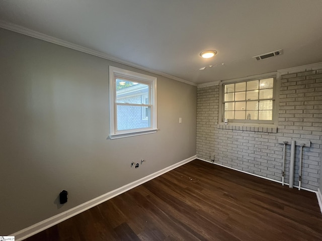 empty room featuring brick wall, ornamental molding, and dark hardwood / wood-style flooring