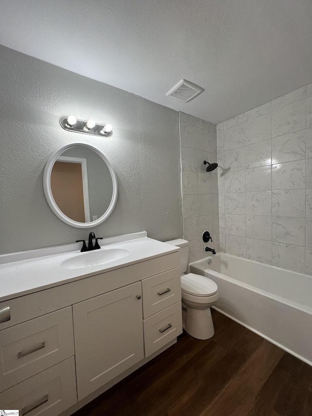 full bathroom with a textured ceiling, tiled shower / bath combo, vanity, toilet, and hardwood / wood-style flooring