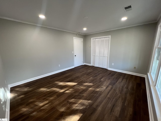 unfurnished bedroom with dark hardwood / wood-style floors, a closet, and crown molding