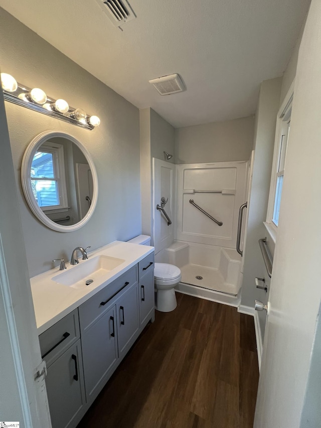 bathroom with a textured ceiling, vanity, a shower, toilet, and hardwood / wood-style flooring