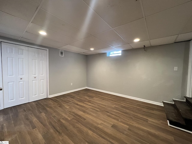 basement featuring dark wood-type flooring and a paneled ceiling