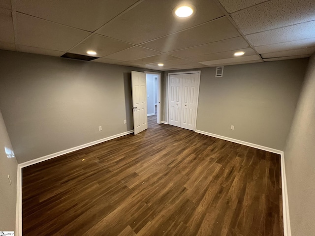 basement with dark hardwood / wood-style floors and a paneled ceiling