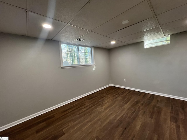 basement featuring dark wood-type flooring and a paneled ceiling