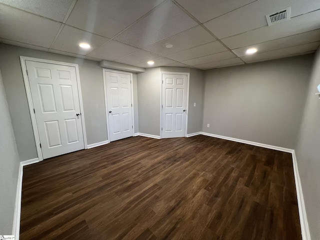 basement featuring dark wood-type flooring and a paneled ceiling