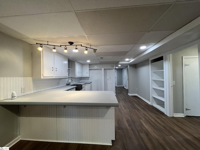 kitchen with dark wood-type flooring, white cabinetry, a paneled ceiling, and kitchen peninsula