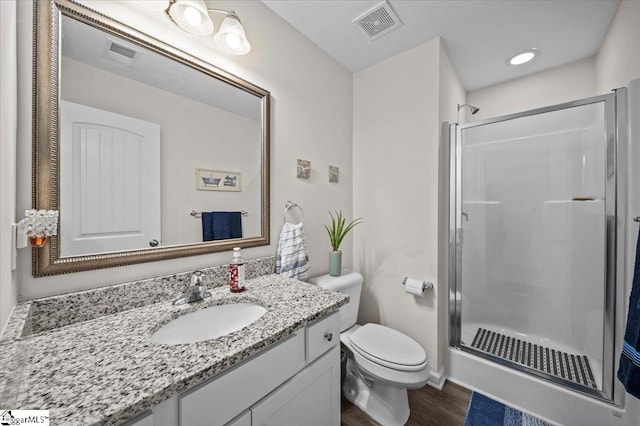 bathroom with hardwood / wood-style floors, an enclosed shower, vanity, and toilet