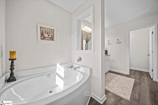 bathroom with hardwood / wood-style floors, a bathtub, and vanity