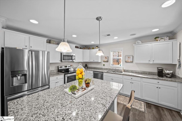 kitchen featuring white cabinets, dark hardwood / wood-style flooring, stainless steel appliances, hanging light fixtures, and ornamental molding