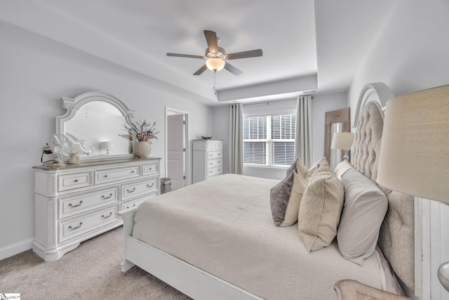 bedroom featuring ceiling fan, light carpet, and a raised ceiling